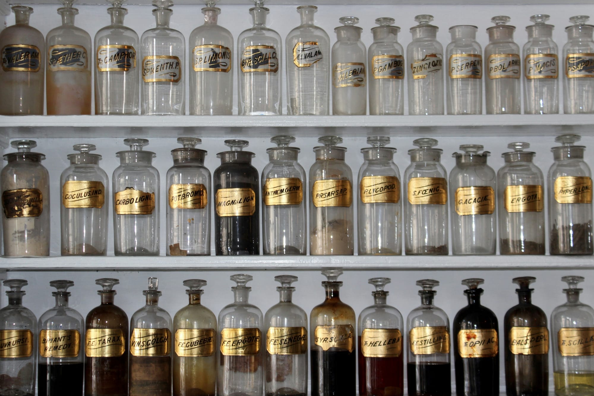 A photo of three shelves containing various glass jars filled with ingredients.